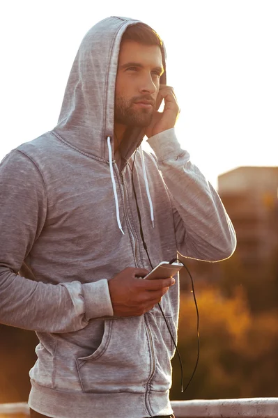 Homme dans les écouteurs tenant téléphone intelligent — Photo