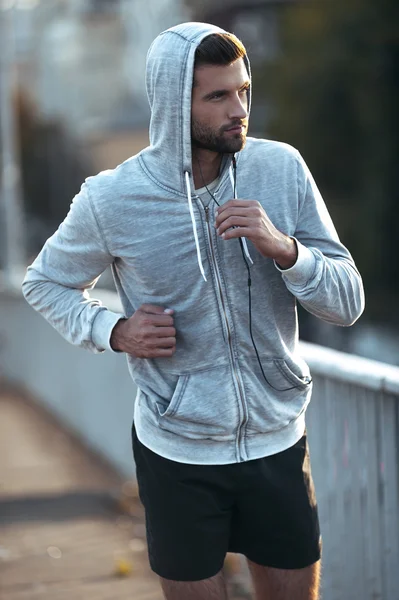 Muscular man looking away while running along the road — Stock Photo, Image