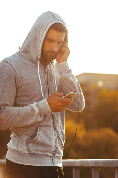 Mann mit Kopfhörer hält Smartphone — Stockfoto