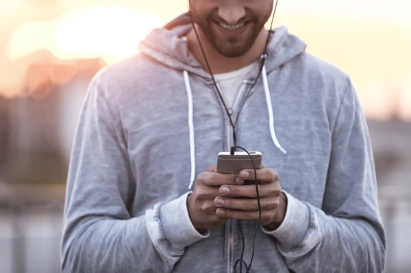 Чоловік в навушниках тримає мобільний телефон — стокове фото