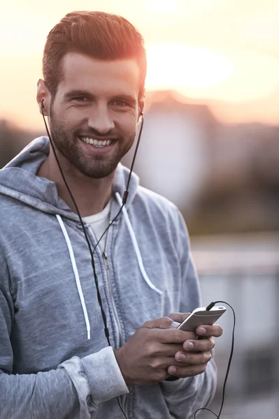 Mann mit Kopfhörer hält Handy in der Hand — Stockfoto