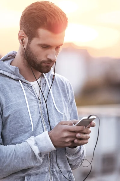 Mann mit Kopfhörer hält Handy in der Hand — Stockfoto