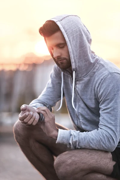 Confident  man checking his pulse while sitting outdoors — Stock Photo, Image