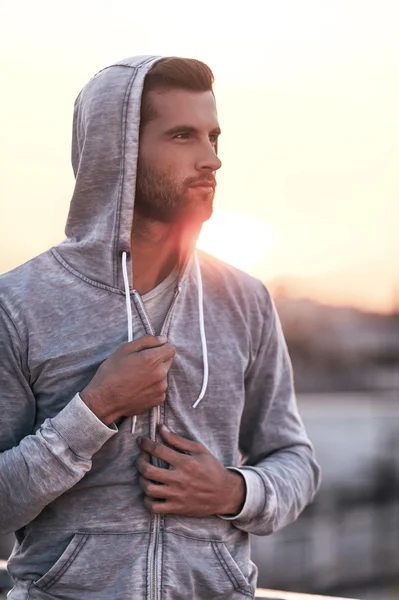 Confident young man adjusting his hoodie — Stock Photo, Image