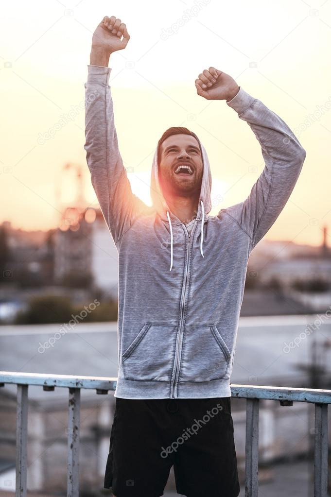 Excited young man keeping arms raised