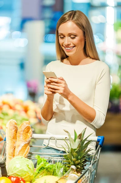 Donna che tiene il telefono cellulare in negozio — Foto Stock