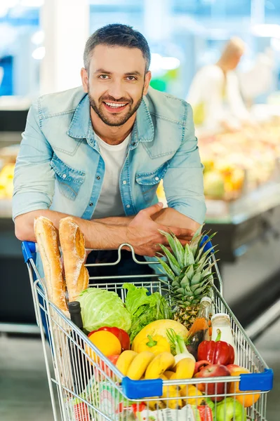 Man lutar sig på kundvagn i butik — Stockfoto