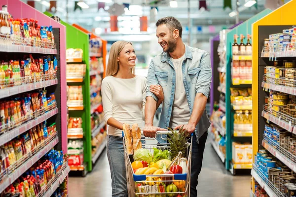 Pareja en tienda de alimentos con carrito de compras — Foto de Stock