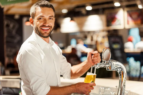 Camarero vertiendo cerveza detrás del mostrador de bar — Foto de Stock