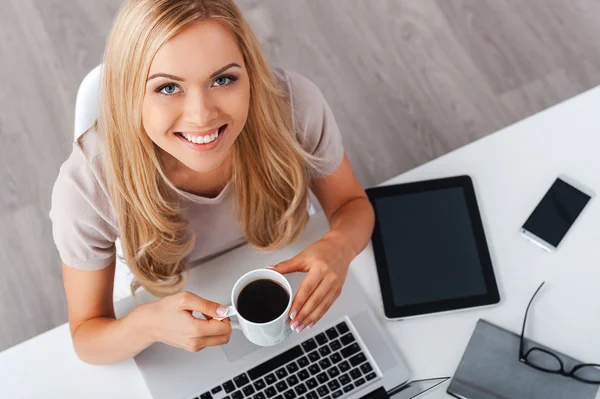 Zakenvrouw met kop koffie op de werkplek — Stockfoto