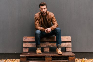 Handsome man sitting on the wooden pallet