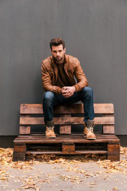 Ahşap palet üzerinde oturan yakışıklı adam