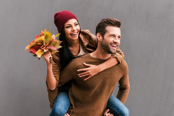 Man meeliften zijn vriendin bedrijf bladeren — Stockfoto