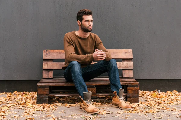 Hombre guapo sentado en la plataforma de madera — Foto de Stock