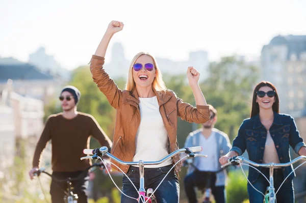 Woman riding bicycle with friends — Stock Photo, Image