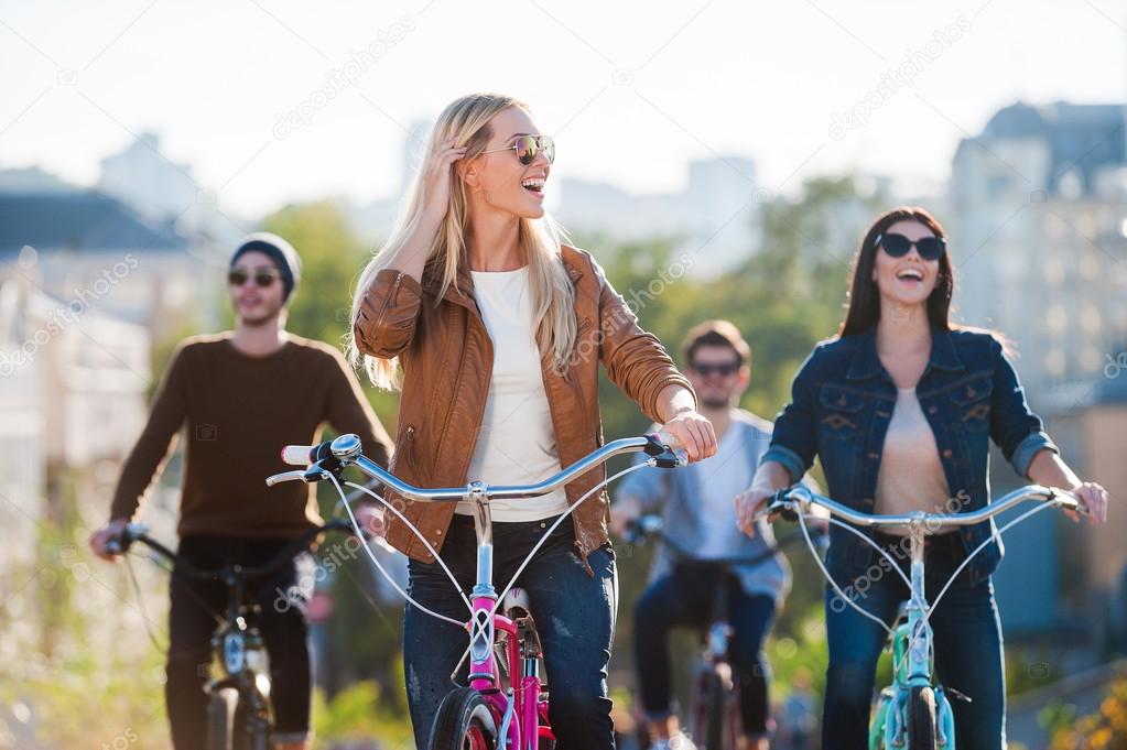 Beautiful Young Smiling Woman Riding Bicycle And Looking Away While Her Friends In The Background Photo By Gstockstudio Beautiful Young Smiling Woman Riding Bicycle And Looking Away While Her Friends In The Background Photo By Gstockstudio