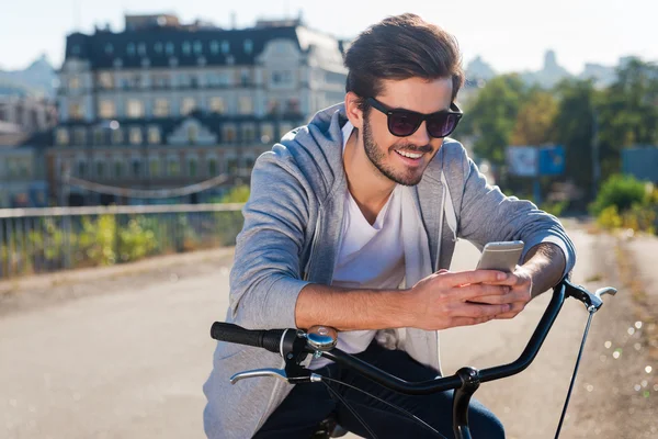 Человек с велосипедом и глядя на свой мобильный телефон — стоковое фото