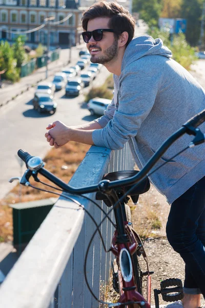 Молодой человек, стоящий возле своего велосипеда — стоковое фото