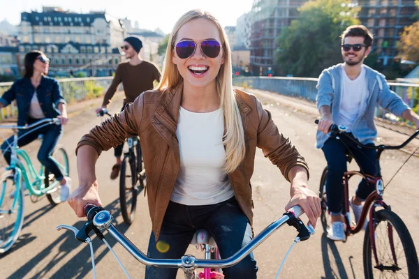 Smiling woman riding bicycle with friends — Zdjęcie stockowe