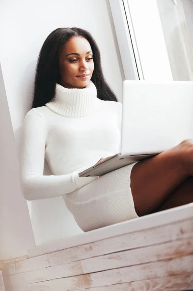 African woman in sweater working on laptop — Stock Photo, Image