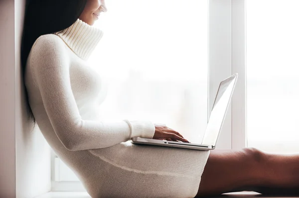 African woman in sweater working on laptop — Stok fotoğraf