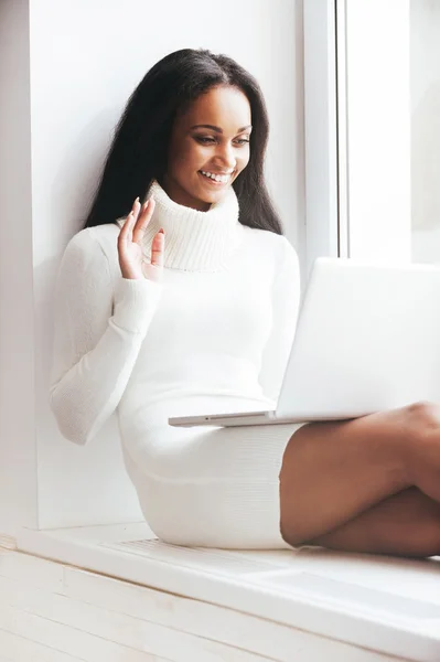 Woman in warm sweater looking at laptop — Stock Photo, Image