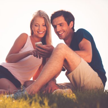 Quayside oturma ve cep telefonu arayan Çift