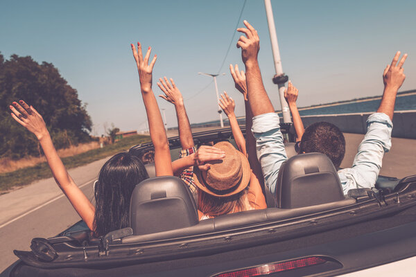 people enjoying road trip in convertible