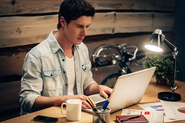 Selvsikker ung mann som jobber med laptop – stockfoto