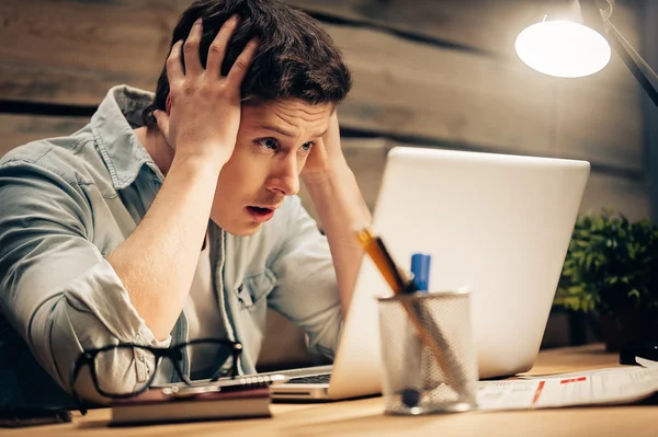 Frustrierter junger Mann schaut auf Laptop — Stockfoto