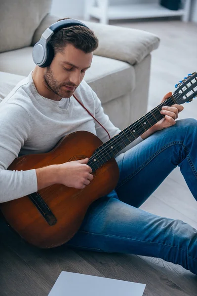 Young man in headphones playing guitar — Stock Photo, Image