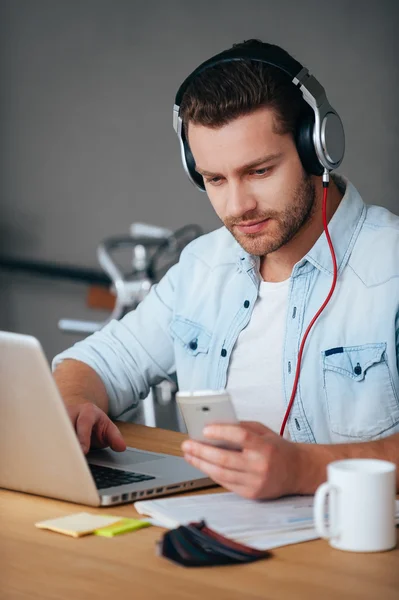 Muž v sluchátka sedět u svého pracovního místa — Stock fotografie