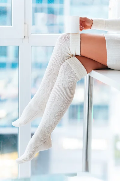 Frau in warmen Socken hält Tasse — Stockfoto