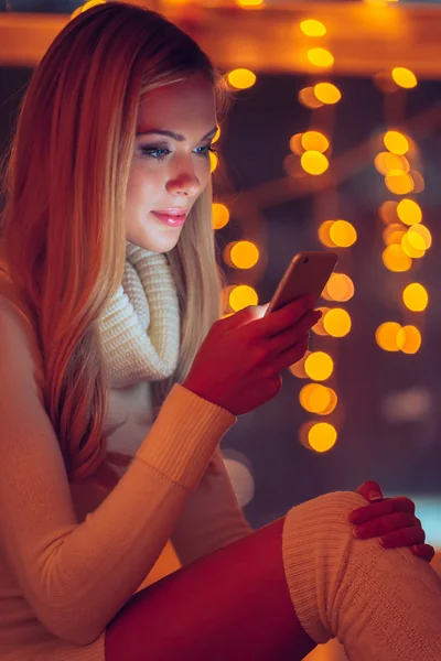 Frau im Pullover hält Smartphone in der Hand — Stockfoto