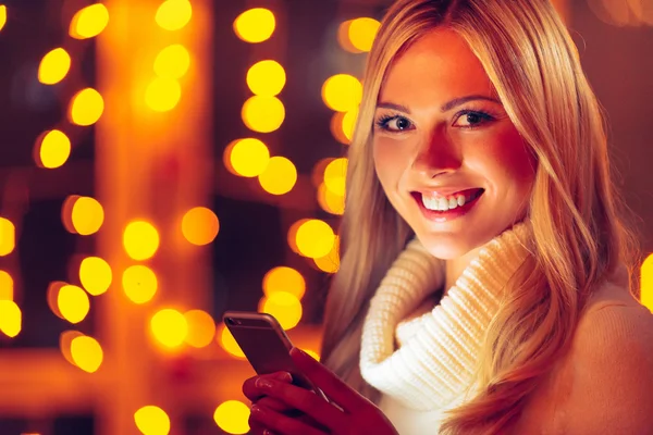 Woman in sweater holding smart phone — Stock Photo, Image