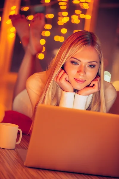 Mujer acostada en el suelo y mirando a la computadora portátil —  Fotos de Stock