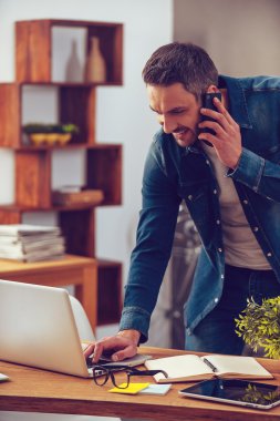 man talking on phone and looking at  laptop