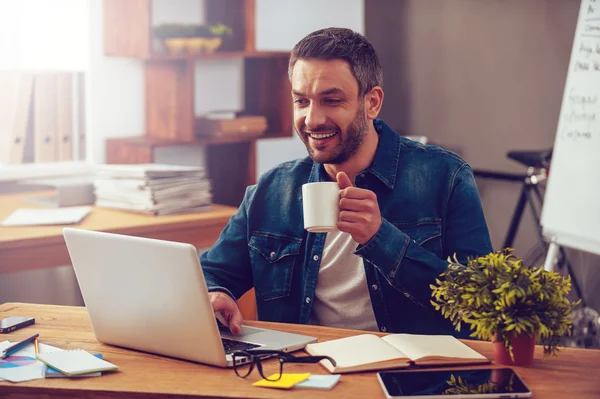 Hombre trabajando en el ordenador portátil y sosteniendo la taza de café —  Fotos de Stock