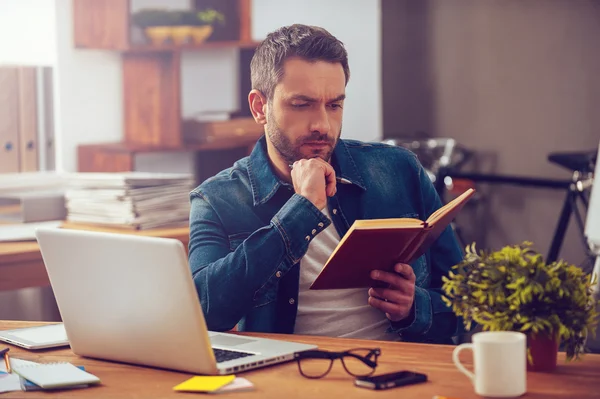 Homme assis à son lieu de travail dans le bureau — Photo