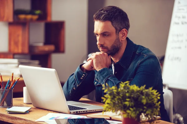 Homem olhando para seu laptop no escritório — Fotografia de Stock