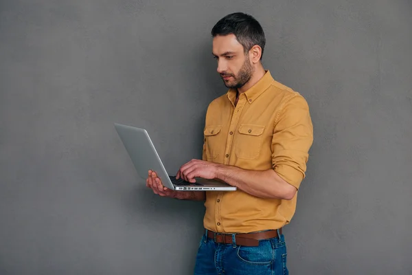 Zelfverzekerde volwassen man die op laptop werkt — Stockfoto