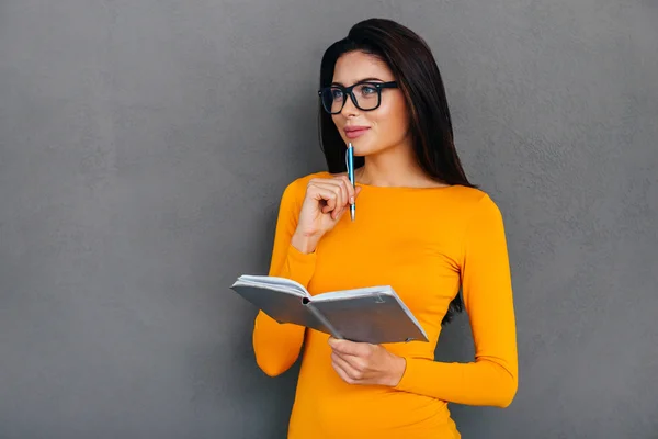 Mujer pensativa sosteniendo un cuaderno — Foto de Stock