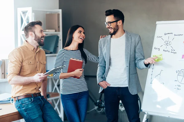 Mann zeigt Whiteboard mit Kollegen in der Nähe — Stockfoto