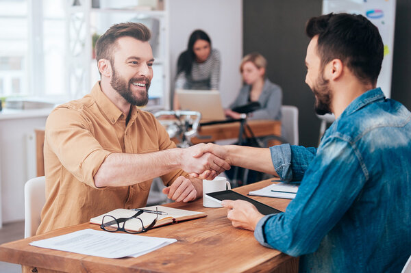young men shaking hands in office