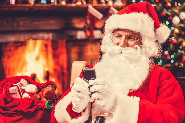 Glücklicher Weihnachtsmann tippt eine Nachricht ein — Stockfoto