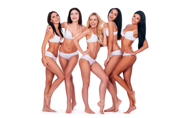 Belleza natural. Longitud completa de cinco hermosas mujeres jóvenes en lencería posando y sonriendo mientras se unen entre sí y de pie sobre fondo blanco — Foto de Stock