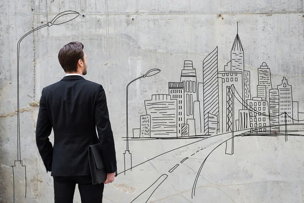 Businessman standing against wall with city sketch — Zdjęcie stockowe