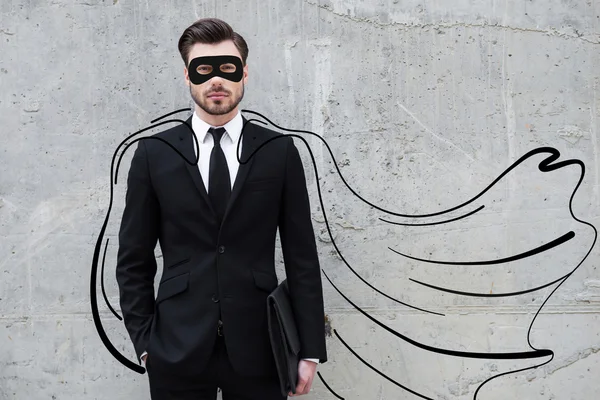 Homem de negócios vestindo uma capa desenhada e máscara enquanto em pé contra a parede de concreto — Fotografia de Stock