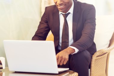 İş adamı dizüstü bilgisayar kullanıyor ve gülümsüyor