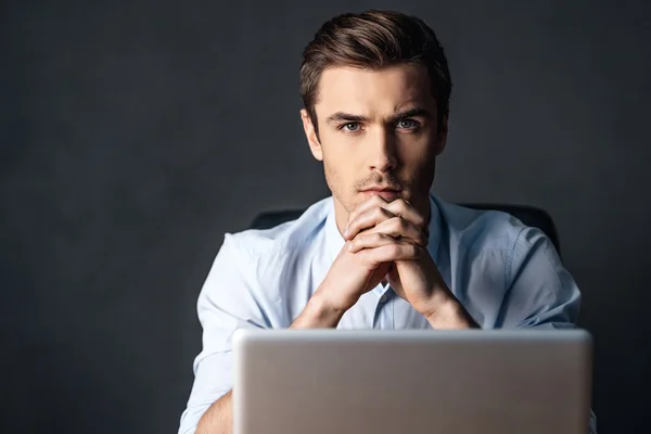 Man with clasped hands over laptop — Stock Photo, Image